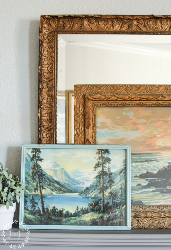paintings stacked on a mantel