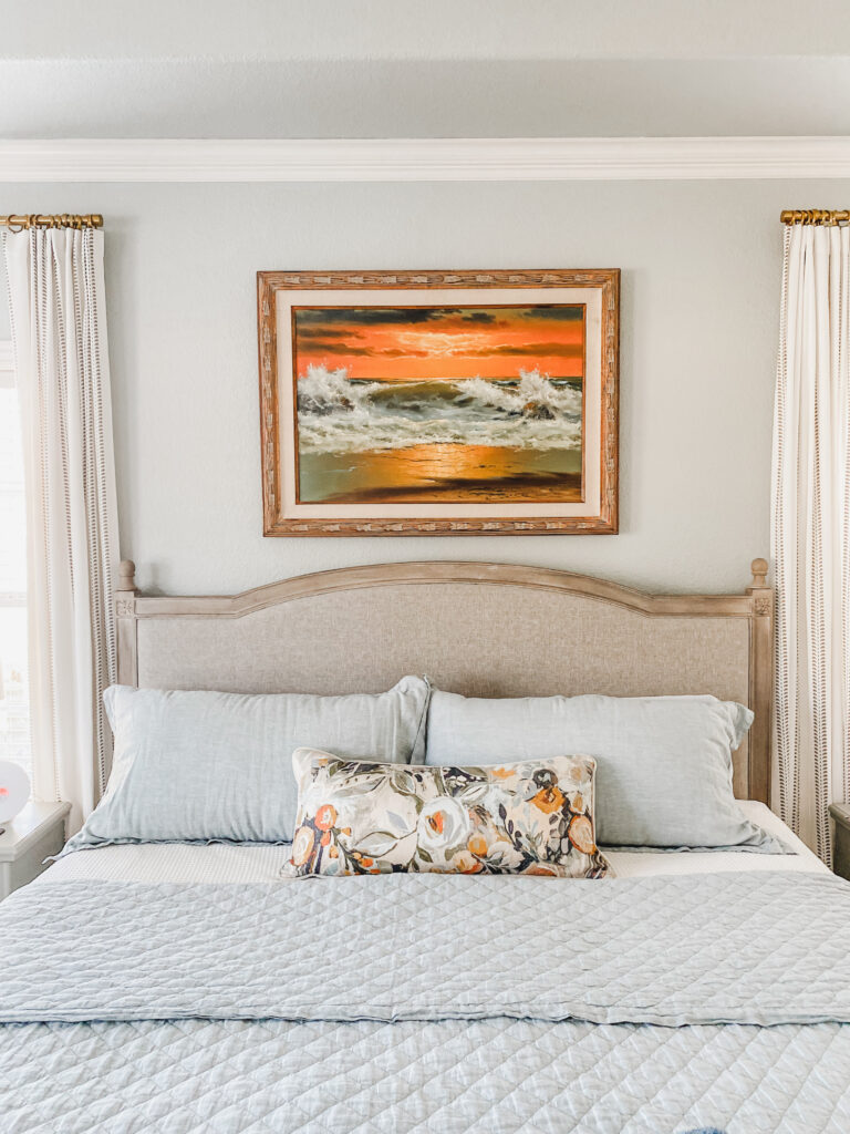 vintage painting hanging in a pretty bedroom
