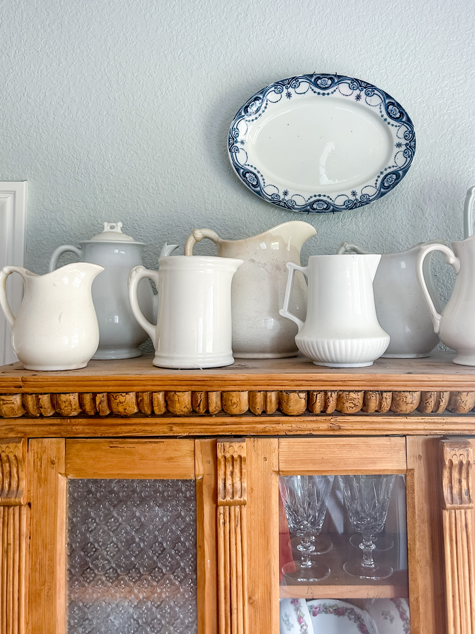 white pitchers displayed on top of an antique cabinet